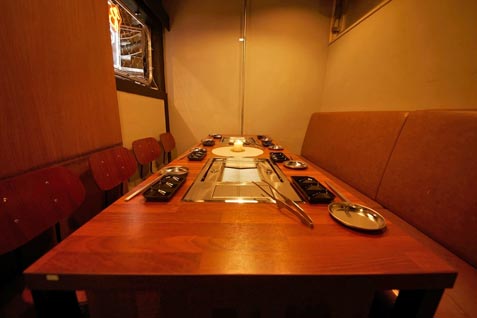 『大阪焼肉 食べ放題 焼肉おにくが好きです 梅田茶屋町店』のテーブル席と無煙ロースター